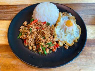 Kızarmış domuz ve fesleğenli pilav ve masada kızarmış yumurta.