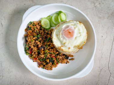 Kızarmış domuz ve fesleğenli pilav ve masada kızarmış yumurta.