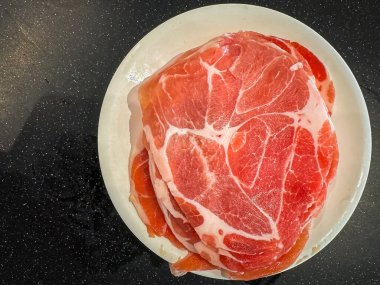 Shabu tenceresinde yemek pişirmek için tabağa domuz eti koy.