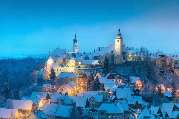 Зимняя ночь в Нове-Место-над-Метуджи, недалеко от Градец Кралове, Чехия. Панорама города с замком на вершине холма, замерзшие деревья. Центр как городской памятник.