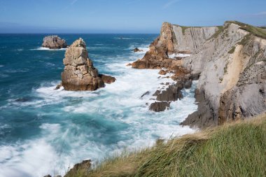 Kuzey İspanya 'da kayalık manzaralı deniz manzarası. Atlantik Okyanusu kıyısı. Güneşli güzel bir gün. Tatil döneminde manzaralı altın kayalıklar ve zümrüt su.