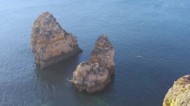 Algarve, Portekiz sahillerinde güneşli bir gün. Arkasında turkuaz deniz var. Algarve kayalıklarının kuş bakışı görüntüsü. Hava görüntüsü. Portekiz 'de seyahat kavramı ve Portekiz' deki en güzel yerler..