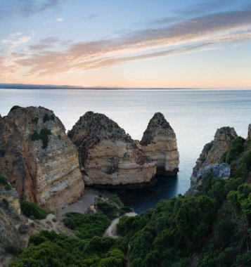 Algarve, Portekiz sahillerinde güneşli bir gün. Arkasında turkuaz deniz var. Algarve kayalıklarının kuş bakışı görüntüsü. Hava görüntüsü. Portekiz 'de seyahat kavramı ve Portekiz' deki en güzel yerler..