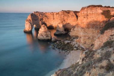 Algarve, Portekiz sahillerinde güneşli bir gün. Arkasında turkuaz deniz var. Algarve kayalıklarının kuş bakışı görüntüsü. Hava görüntüsü. Portekiz 'de seyahat kavramı ve Portekiz' deki en güzel yerler..