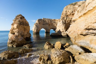 Algarve, Portekiz sahillerinde güneşli bir gün. Arkasında turkuaz deniz var. Algarve kayalıklarının kuş bakışı görüntüsü. Hava görüntüsü. Portekiz 'de seyahat kavramı ve Portekiz' deki en güzel yerler..