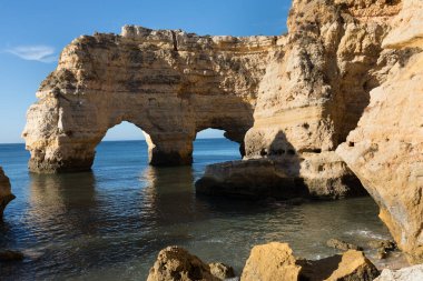 Algarve, Portekiz sahillerinde güneşli bir gün. Arkasında turkuaz deniz var. Algarve kayalıklarının kuş bakışı görüntüsü. Hava görüntüsü. Portekiz 'de seyahat kavramı ve Portekiz' deki en güzel yerler..