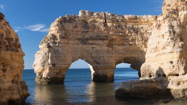 Algarve, Portekiz sahillerinde güneşli bir gün. Arkasında turkuaz deniz var. Algarve kayalıklarının kuş bakışı görüntüsü. Hava görüntüsü. Portekiz 'de seyahat kavramı ve Portekiz' deki en güzel yerler..