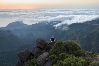 Dağın tepesinde yürüyüş yapan genç bir adamın görüntüsü.