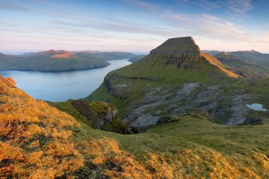 Faroe Adaları 'nın tepesinde. Güneşli bir günde yüksek dağ zirveleri manzarası. Okyanus manzaralı. Güzel panoramik manzara. Kuzey Avrupa. Seyahat kavramı
