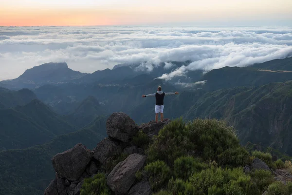 Dağın tepesinde yürüyüş yapan genç bir adamın görüntüsü.