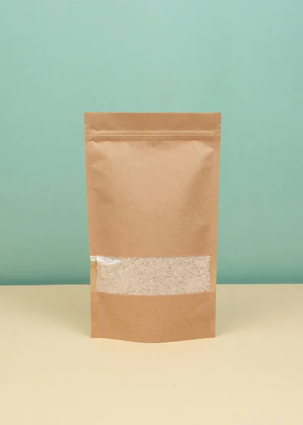 Brown kraft paper doypack bags with groceries front view on a yellow background. Packaging for foods and goods template mock-up. Packs with windows for weight products.