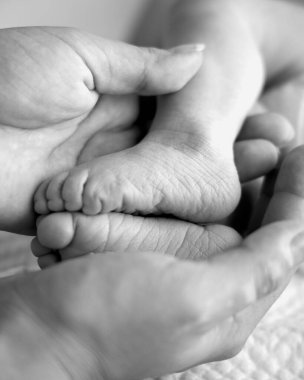 Yeni doğmuş bir bebeğin küçük ayakları. Bir bebeğin hayatının ilk günleri. Siyah ve beyaz çekim.