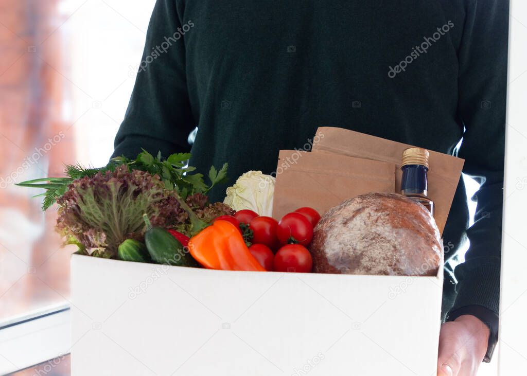 A person delivering box with farmer bio crop in the house doorway. Fresh organic greens and vegetables delivery. Small local business support. Online grocery shopping
