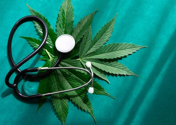 Medyczna marihuana olej cbd konopi z stetoskopem na zielonym tle z odcieniami. — Zdjęcie stockowe
