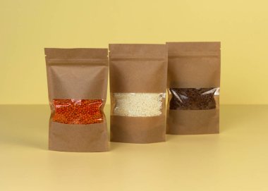 Kahverengi kraft kağıdından çanta, sarı arka planda market önü manzaralı. Gıda ve mallar için ambalaj tasarımı. Ağırlık ürünleri için pencereli paketler. Moda rengi