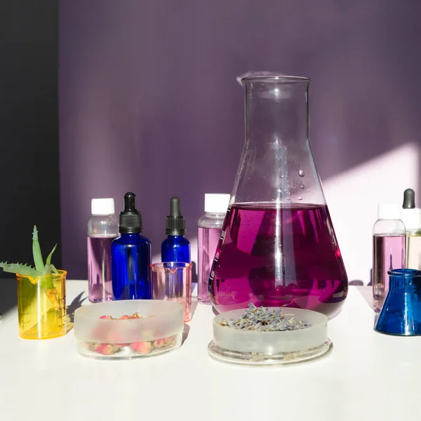 Abstract cosmetic or chemical laboratory. Laboratory equipment, flasks, test tubes, petri dishes. Creative concept with hard shadows. Flat lay.