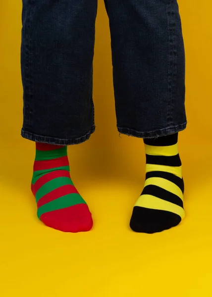 Legs with multicolored different stripes socks on background with copy space. World Down syndrome day background. Down syndrome awareness concept.