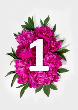 Layout with pink peonies flowers and number one sign. Flat lay. View from above.
