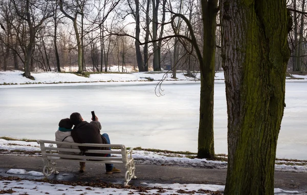 Pareja sentada junto al lago en la tarde de invierno — Foto de Stock