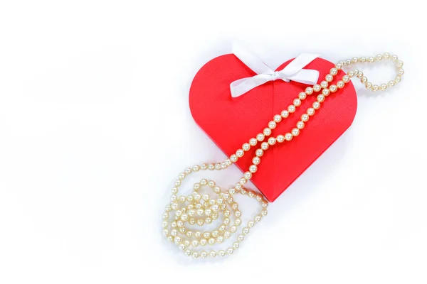 Red gift box in shape of a heart and string of pearls Stock Picture