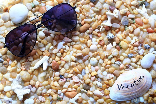 Gafas de sol en la playa de guijarros - vacaciones de verano — Foto de Stock