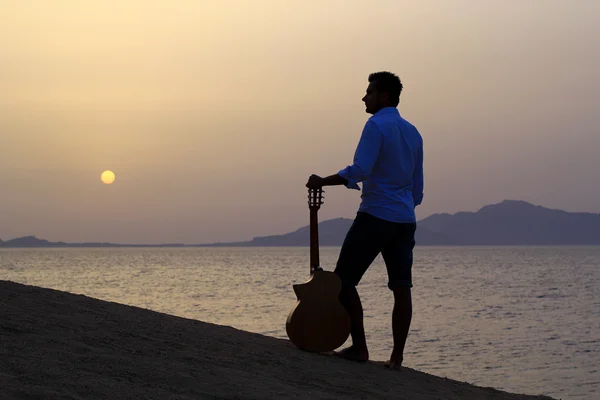 看着早晨的阳光下的海滩上的吉他手 — 图库照片