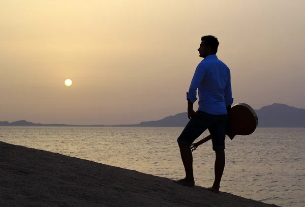 Guitarrista en la playa viendo el sol de la mañana — Foto de Stock