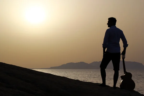 Guitarrista en la playa viendo el sol de la mañana — Foto de Stock