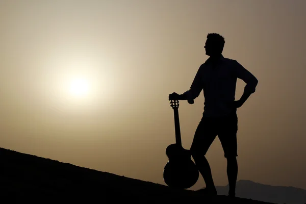 Gitarist op het strand kijken naar de ochtendzon — Stockfoto