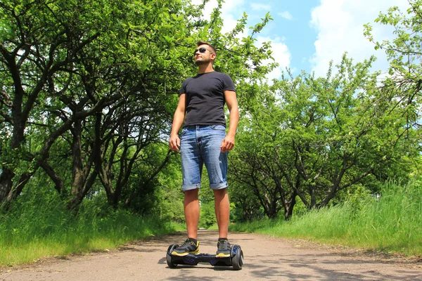 Homem montando uma scooter elétrica no parque — Fotografia de Stock