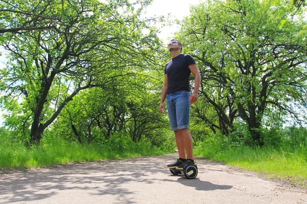 Ember lovaglás egy elektromos robogó, a parkban — Stock Fotó