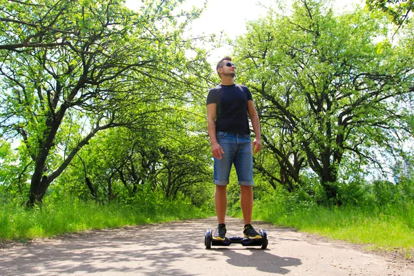 Hombre montando un scooter eléctrico en el parque — Foto de Stock