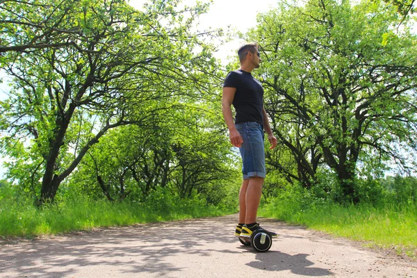 Ember lovaglás egy elektromos robogó, a parkban — Stock Fotó