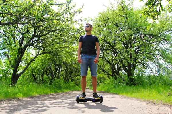 Ember lovaglás egy elektromos robogó, a parkban — Stock Fotó