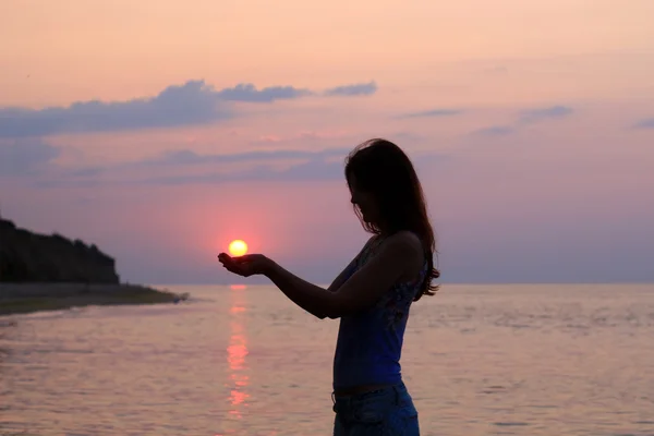 Silueta de mujer sosteniendo el sol en sus palmas — Foto de Stock