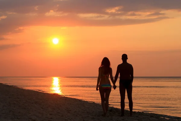 Koppel op het strand bij zonsopgang Stockafbeelding