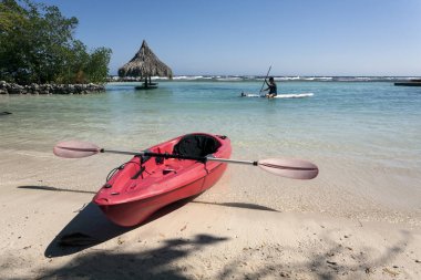 Sahilde kırmızı kano, arka planda kürek tahtası. Roatan Honduras 'ta Karayip Otantik Seyahati