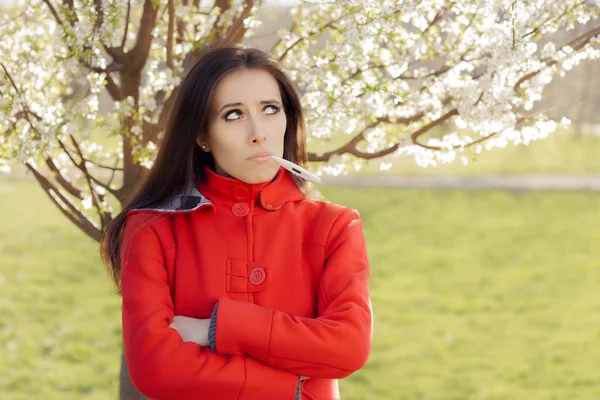 Mujer triste con termómetro en primavera decoración floreciente —  Fotos de Stock