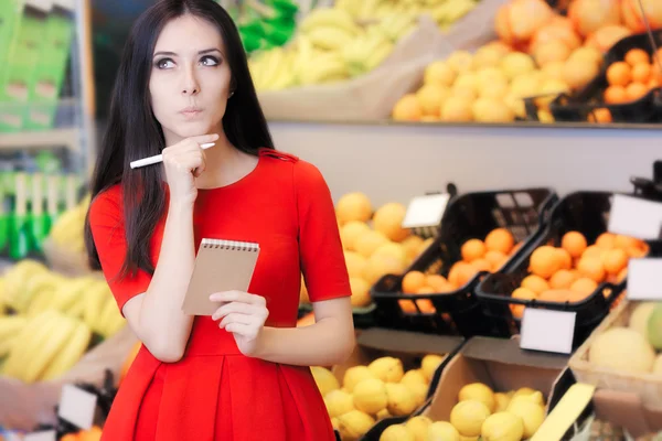 Курьезная женщина в супермаркете со списком покупок — стоковое фото