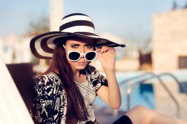 Sürpriz kız ile güneş gözlüğü ve şapka oturan şezlong üzerinde