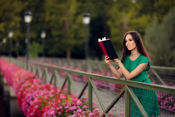 Γυναίκα ανάγνωση ενός βιβλίου σε μια γέφυρα με λουλούδια — Φωτογραφία Αρχείου