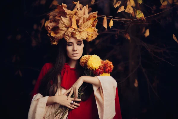 Mulher bonita com outono deixa coroa segurando flores — Fotografia de Stock