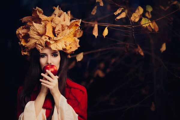 Portrait of a fall princess with foliage wreath holding a fruit