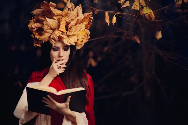 Vrouw met herfst bladeren kroon lezen van een boek — Stockfoto