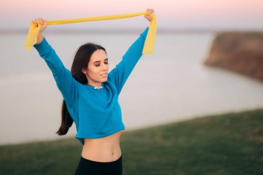 Kollarını esnetme egzersizi için Yoga Bandı kullanan Kadın