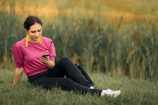 Glückliche Frau Sitzt Gras Und Checkt Smartphone — Stockfoto