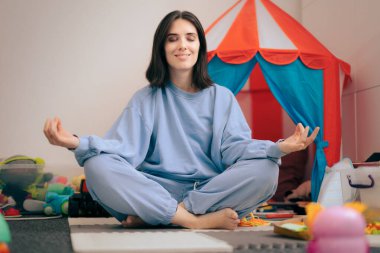 Gamsız Anne Lotus pozisyonunda oturuyor Oyuncaklarla çevrili