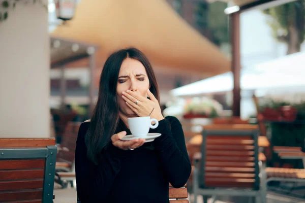Sleepy Woman Holding a Cup of Coffee in a Restaurant