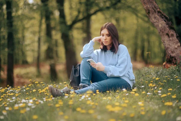 自然の中で座っている女性彼女のスマートフォンをチェック — ストック写真