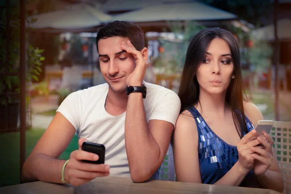 Hemlighetsfulla par med smarta telefoner i händerna — Stockfoto